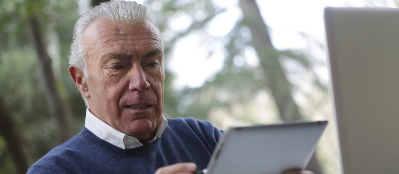 Starszy człowiek używa tabletu.